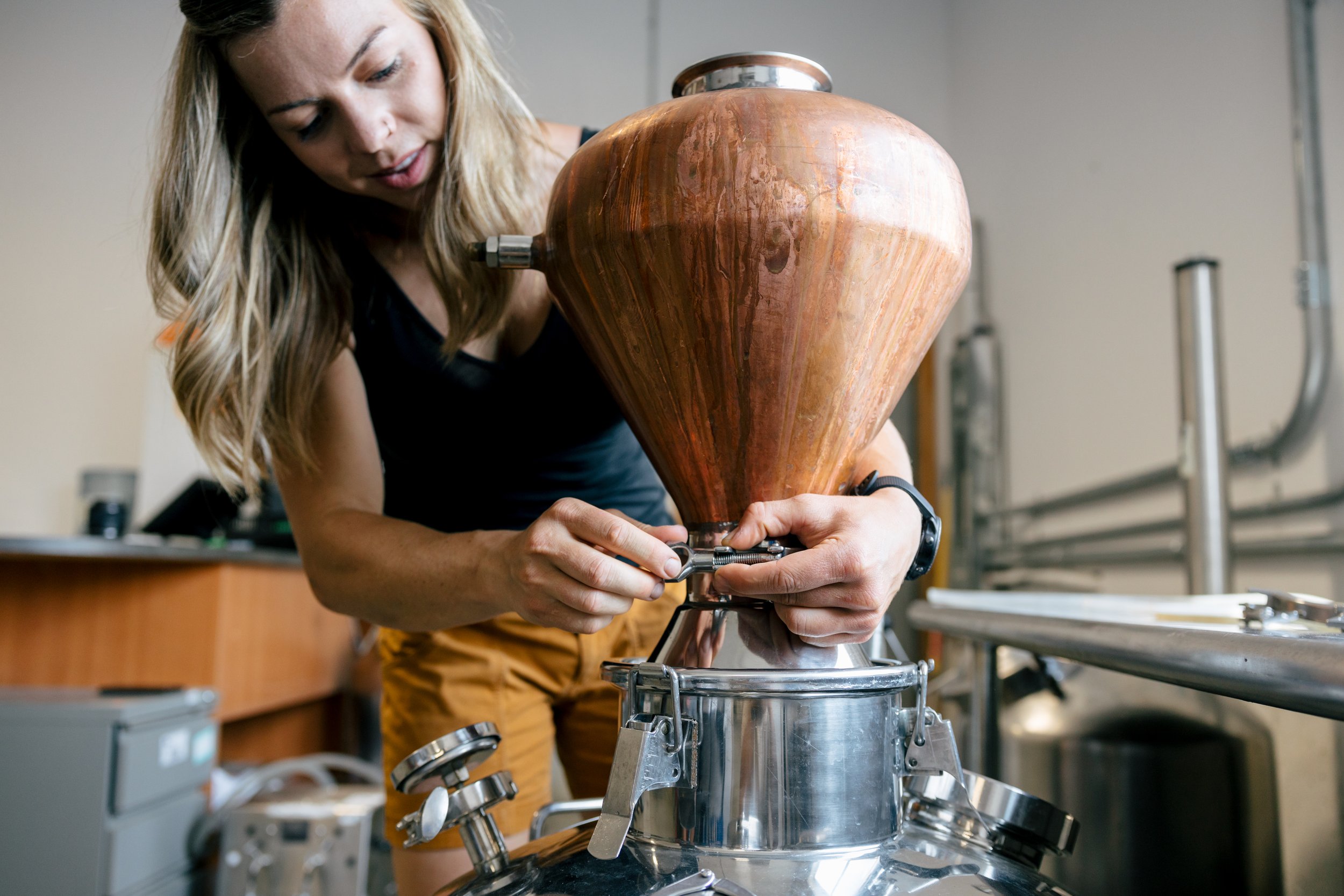 Woman working with a piece of equipment that has a large, wooden, cone-shaped component, possibly related to scientific or industrial processes.